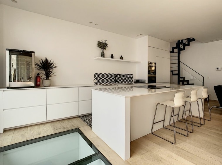 Cuisine moderne lumineuse avec îlot central, backsplash noir et blanc, design épuré et élégant.