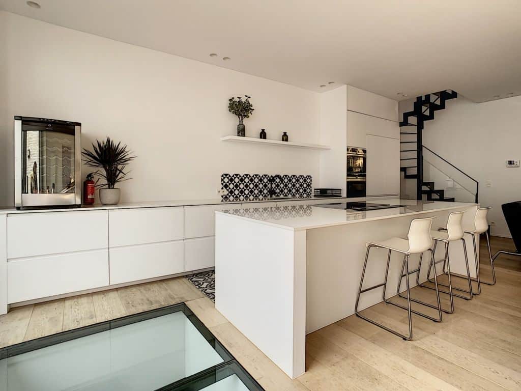 Cuisine moderne lumineuse avec îlot central, backsplash noir et blanc, design épuré et élégant.
