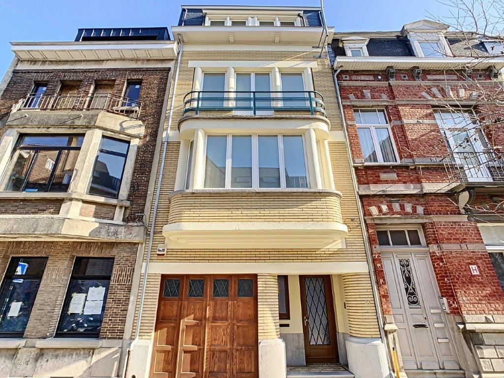Résidence urbaine moderne à trois étages avec grandes fenêtres, balcon et façade jaune lumineuse.