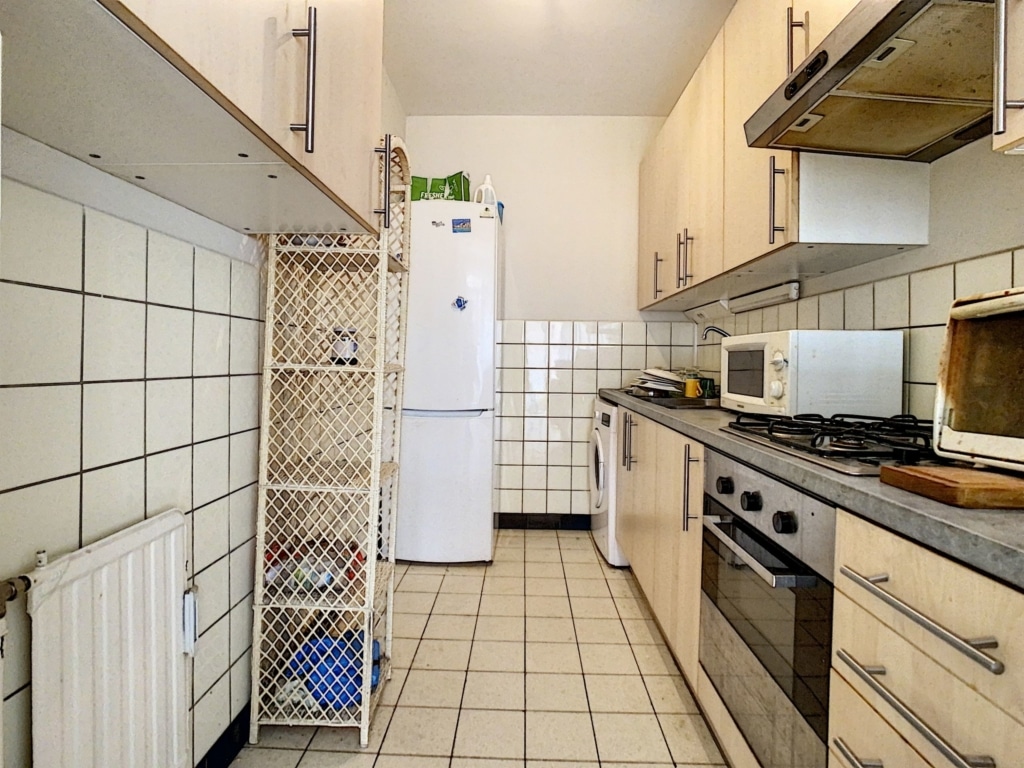Cuisine moderne lumineuse avec électroménagers contemporains, rangement pratique et style épuré.