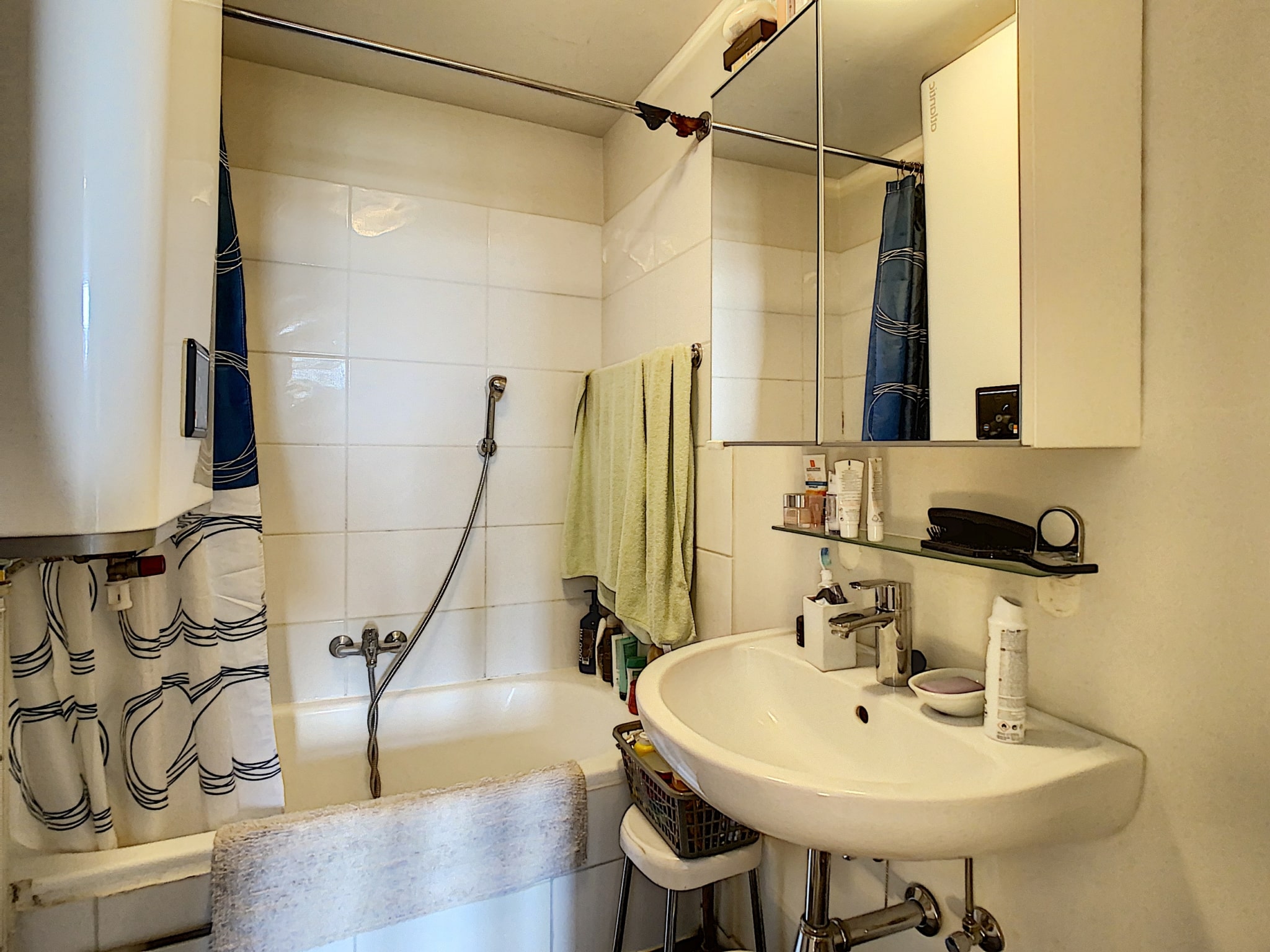 Salle de bain moderne et pratique avec lavabo rond, miroir, douche et décoration épurée.