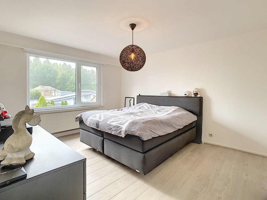Chambre moderne lumineuse avec lit noir, décoration épurée et lumière naturelle.