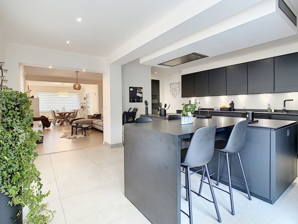 Cuisine ouverte design moderne avec îlot, électroménagers intégrés et ambiance chaleureuse.