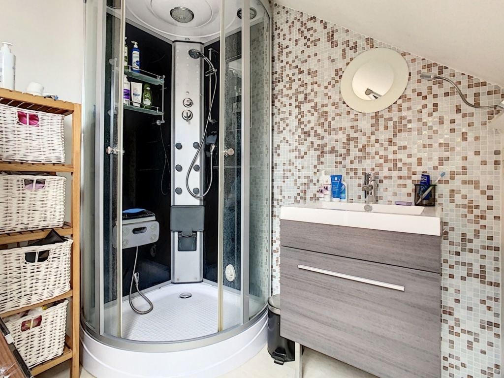 Salle de bain moderne avec douche à litalienne, mosaïque élégante et rangement en osier.