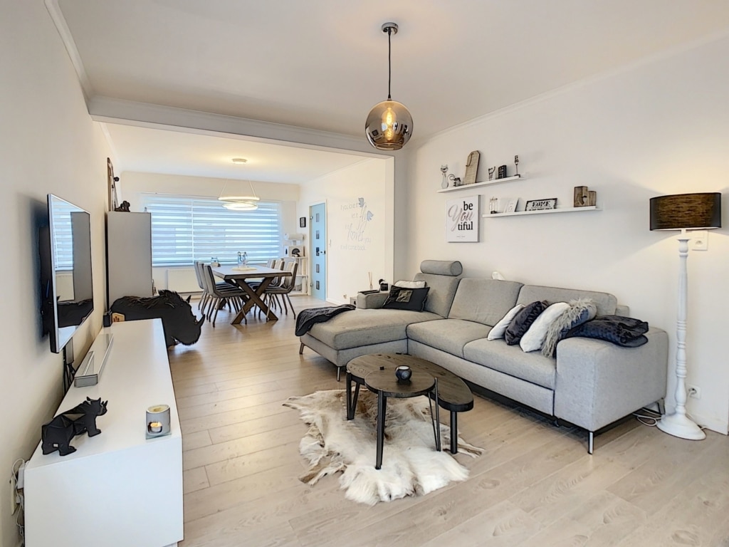 Salon contemporain élégant avec canapé gris, espace repas moderne, décor chic et lumineux.