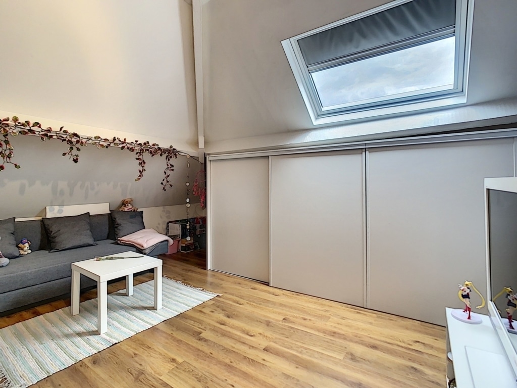 Salon moderne et cosy avec lumière naturelle, canapé gris, parquet clair, décor minimaliste.