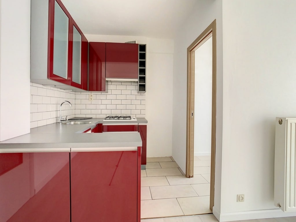 Cuisine moderne avec placards rouges brillants, plan gris clair, espace pratique et lumineux.