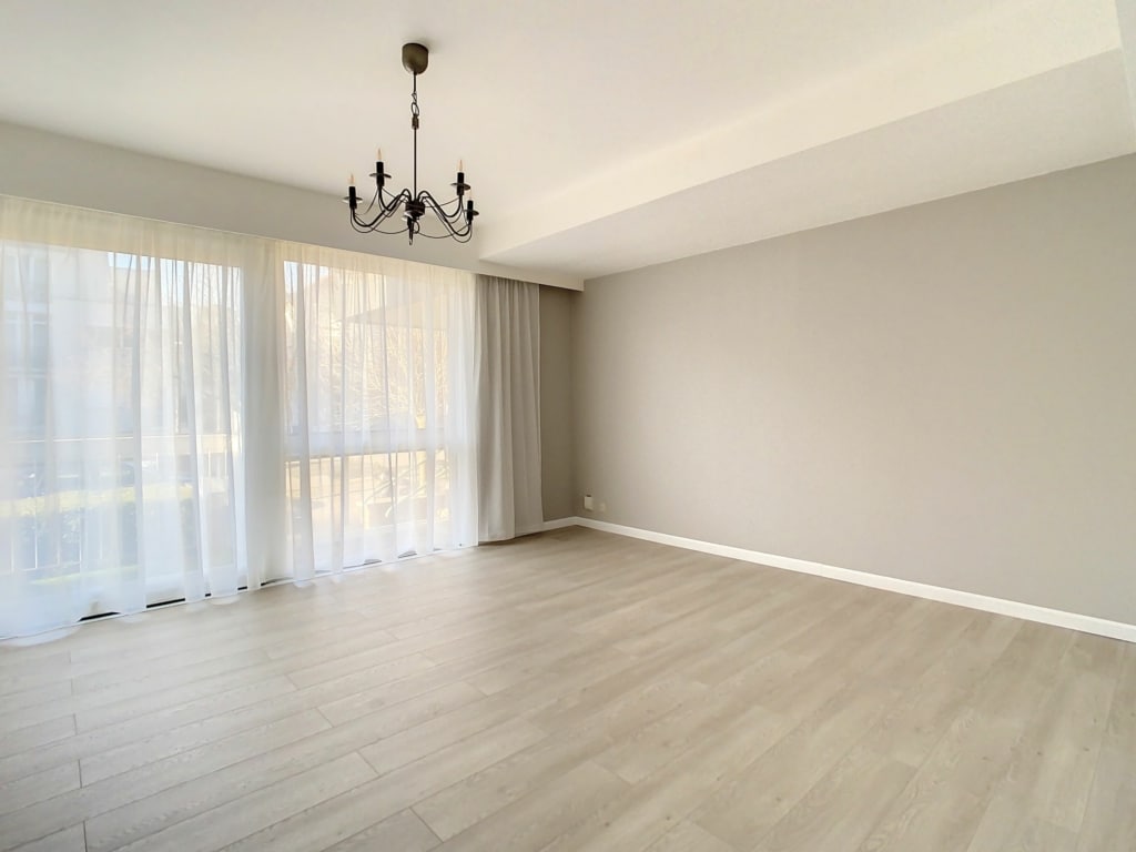 Salon moderne lumineux avec murs gris, parquet clair et grand fenêtres pour une ambiance élégante.