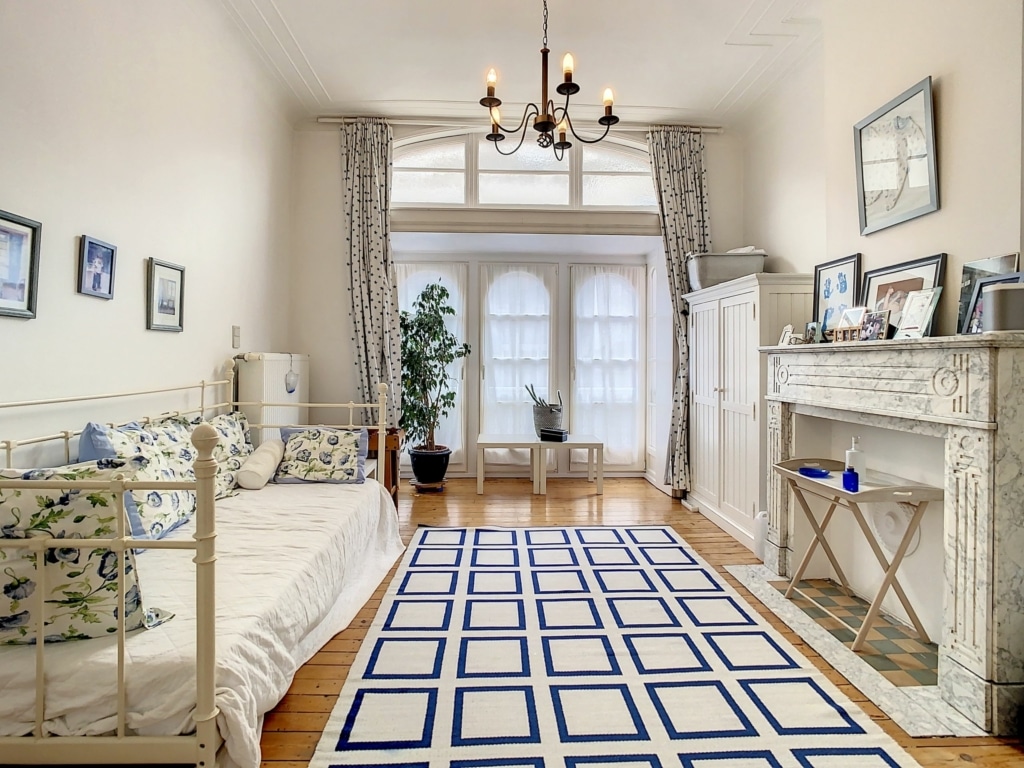 Salon lumineux avec canapé, tapis géométrique bleu, cheminée ancienne et décoration élégante