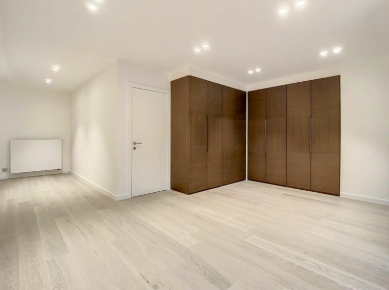 Intérieur minimaliste lumineux avec grand placard en bois foncé, murs blancs et sol en bois clair.