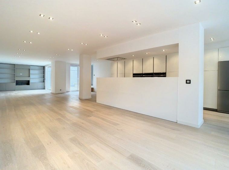 Salon moderne lumineux avec cuisine ouverte, mur en pierre et cheminée cosy.