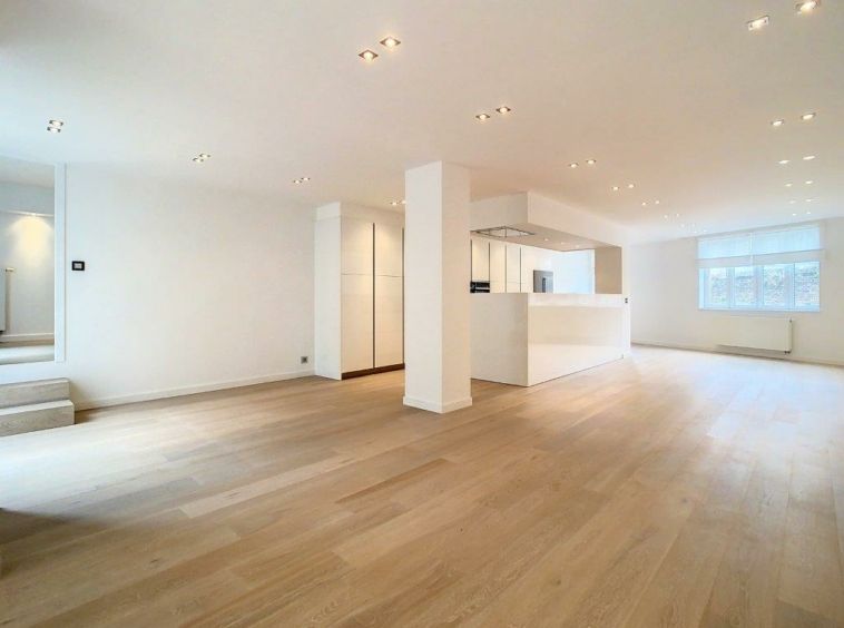 Salon moderne avec cuisine lumineuse et design minimaliste, lumière naturelle et ambiance épurée.