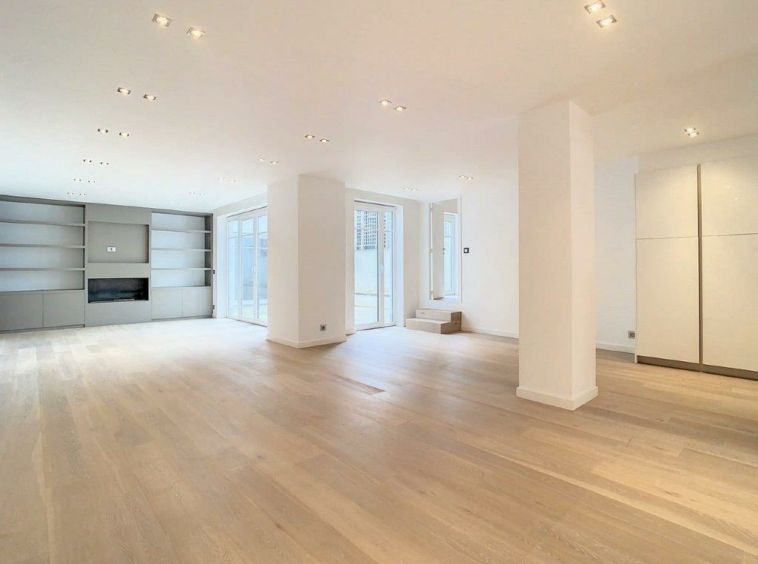 Salon contemporain lumineux avec grandes fenêtres, murs blancs, mobilier épuré et style minimaliste.