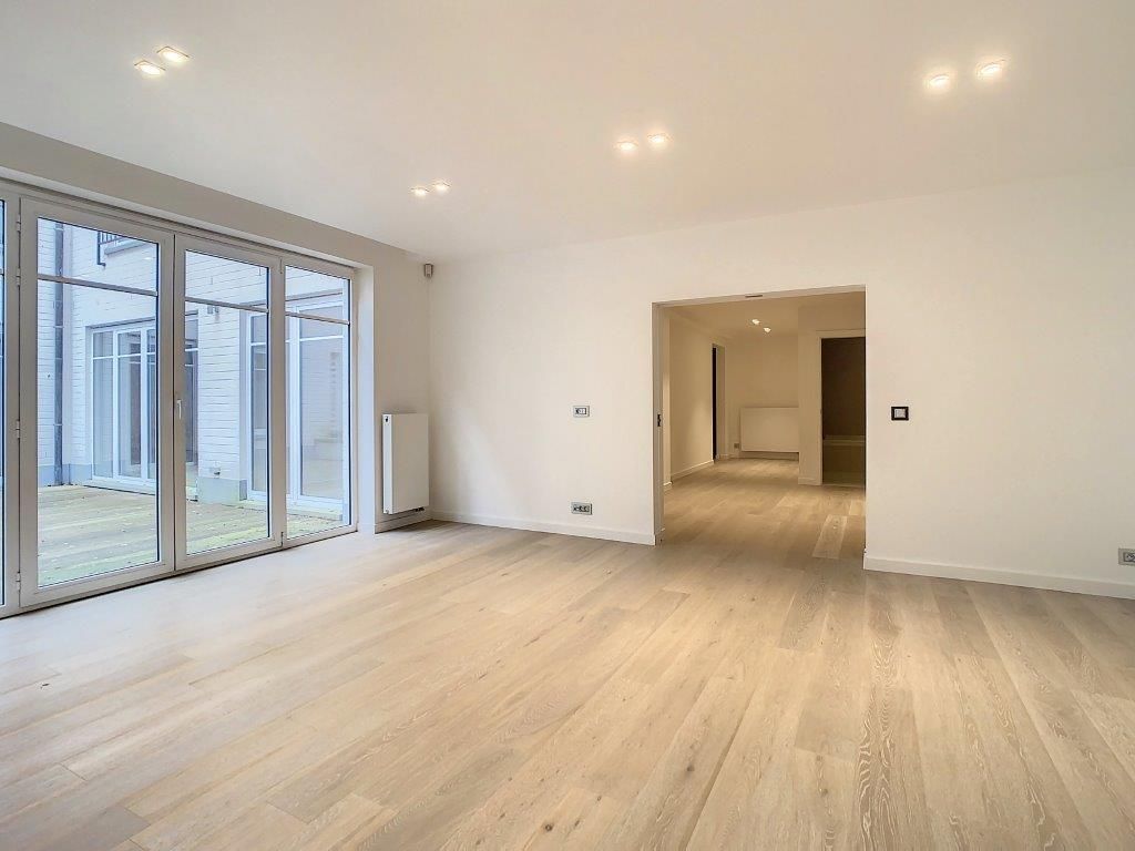 Salon lumineux avec grandes portes vitrées, parquet clair, espace ouvert et ambiance moderne.