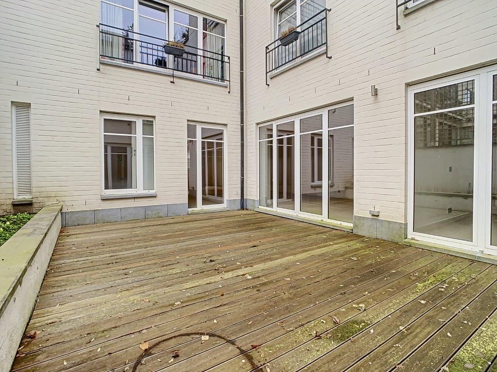 Terrasse moderne en bois avec grandes fenêtres, balcons privés, espace extérieur lumineux.