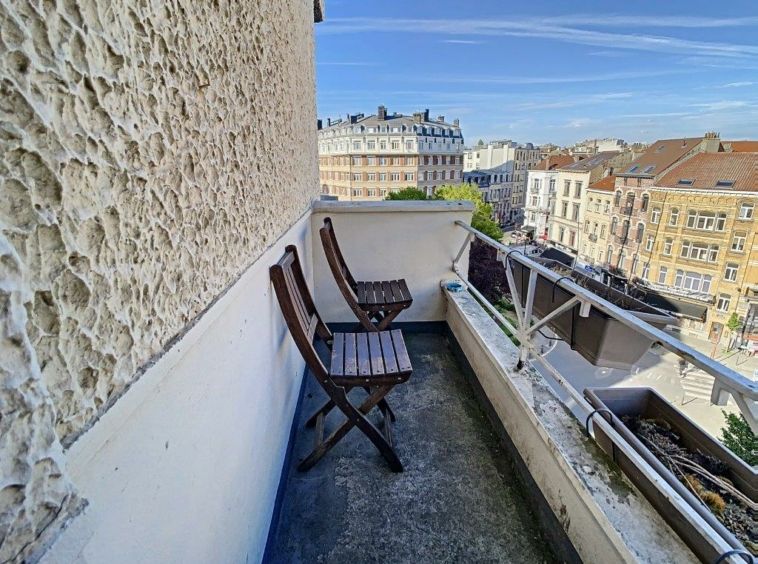 Balcon urbain avec vue, chaises en bois, ambiance paisible et vue sur la ville.