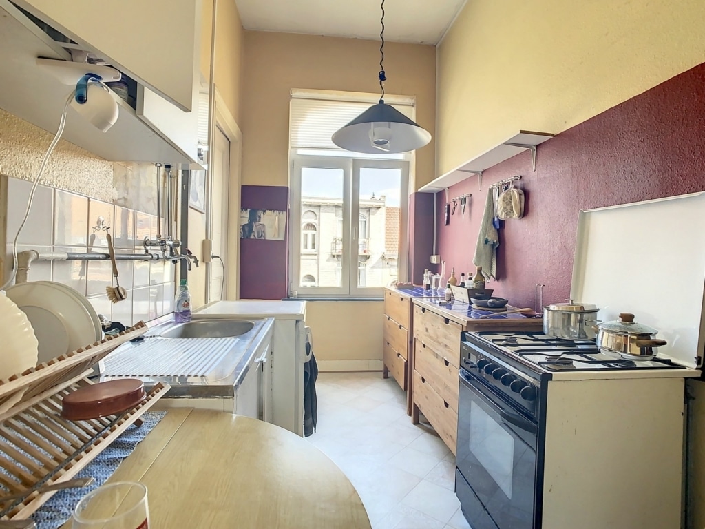 Cuisine vintage chaleureuse avec faïence beige, fenêtre lumineuse, mobilier en bois et accessoires traditionnels.