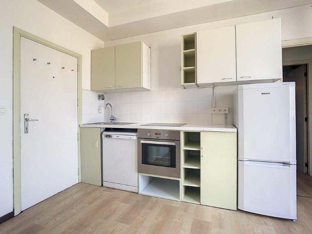 Cuisine moderne lumineuse avec meubles verts, blanc, plan quartz, appareils intégrés, espace ouvert.