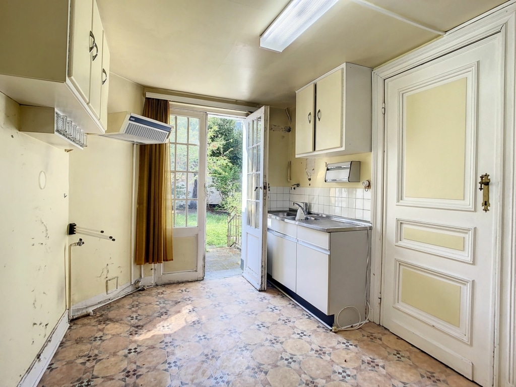 Cuisine vintage accueillante avec accès jardin, lumière naturelle, charme d’époque, parfaite pour moments familiaux.