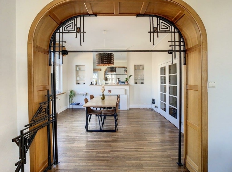 Intérieur moderne élégant avec arche en métal et bois, salle lumineuse, mobilier minimaliste.