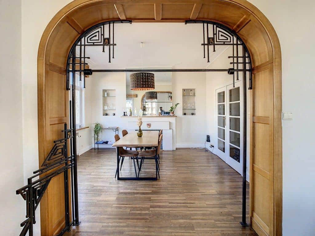 Intérieur moderne élégant avec arche en métal et bois, salle lumineuse, mobilier minimaliste.