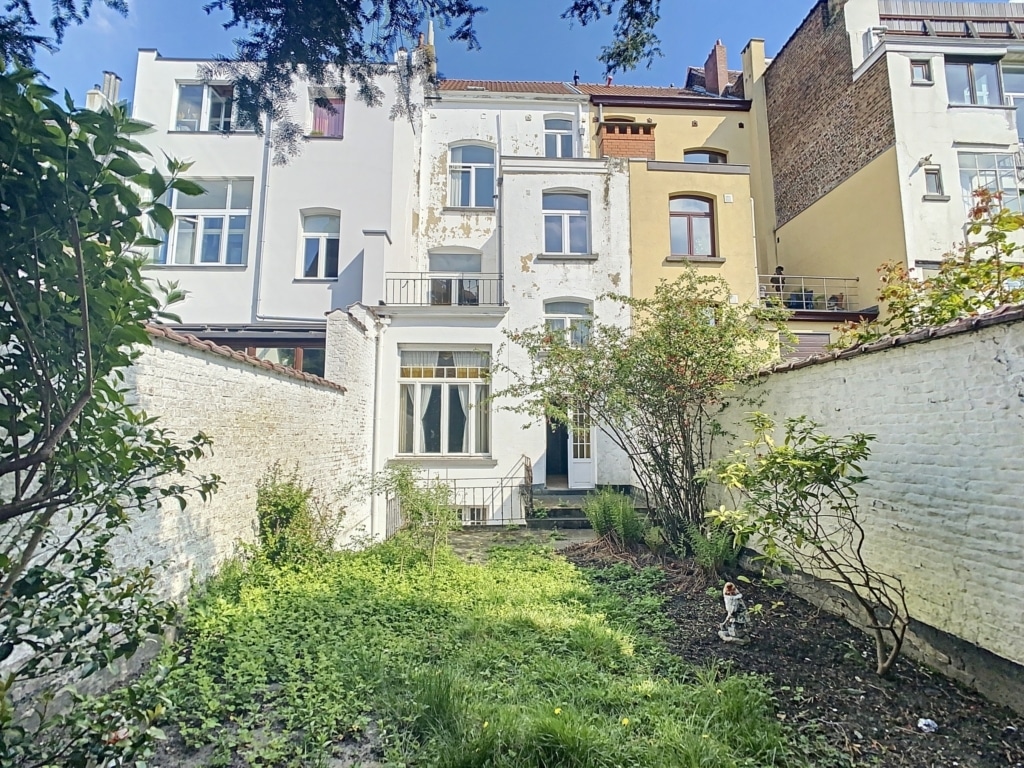 Jardin urbain verdoyant entre bâtiments colorés et architecture variée sous un ciel bleu clair.
