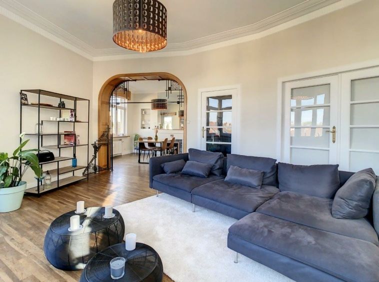 Salon moderne avec canapé gris, étagère design, lumière élégante et ambiance chaleureuse.