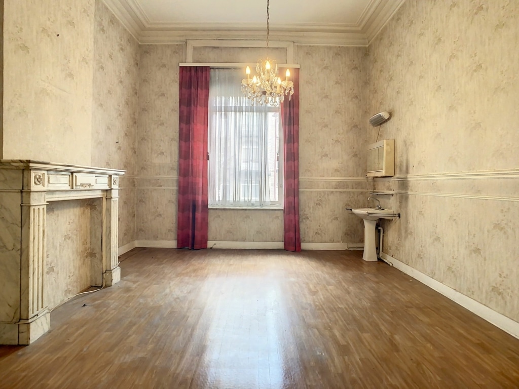 Salon vintage élégant avec cheminée ornée, lustre en cristal et murs décoratifs raffinés.
