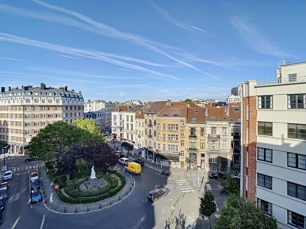 Vue charmante dune rue européenne animée avec rond-point, fontaine, bâtiments colorés et circulation.