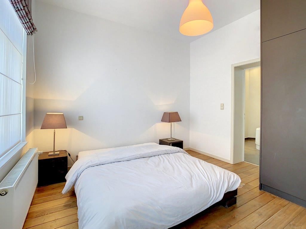 Chambre minimaliste lumineuse avec lit blanc, bois clair, lumière naturelle, ambiance sereine et chaleureuse.