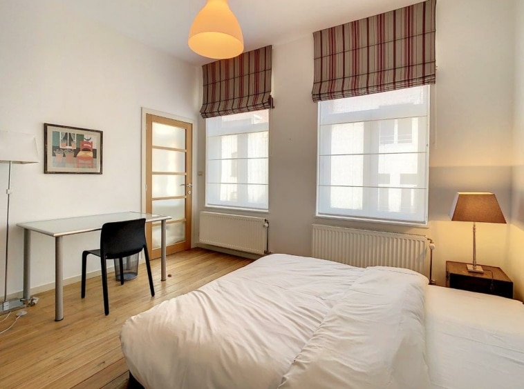 Chambre lumineuse et moderne avec lit blanc, bureau minimaliste et décoration naturelle apaisante.