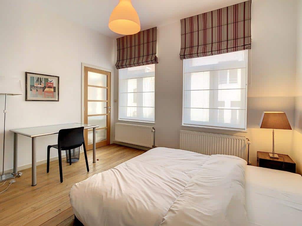 Chambre lumineuse et moderne avec lit blanc, bureau minimaliste et décoration naturelle apaisante.