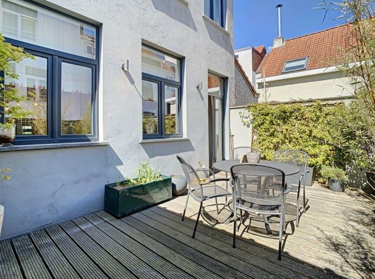 Coin patio urbain cosy avec mobilier métallique, plantes verdoyantes, lumière naturelle et ambiance détendue.