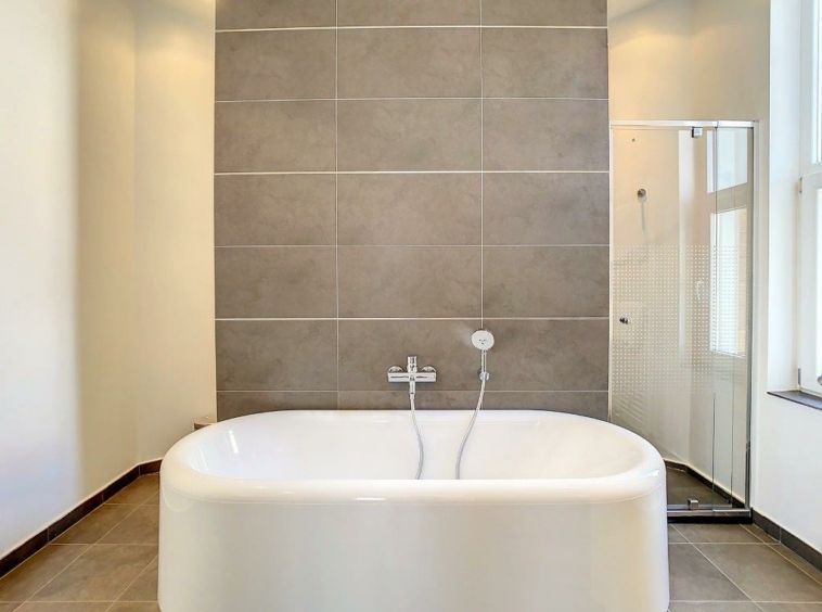 Salle de bain moderne avec baignoire blanche, douche en verre et ambiance lumineuse élégante.