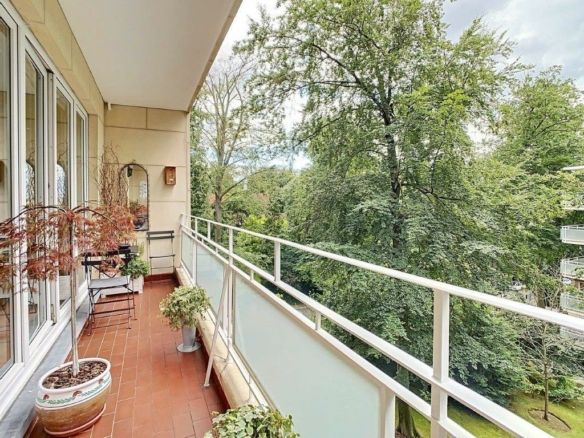 Peaceful balcony with plants, comfortable furnishings and views of a lush forest.