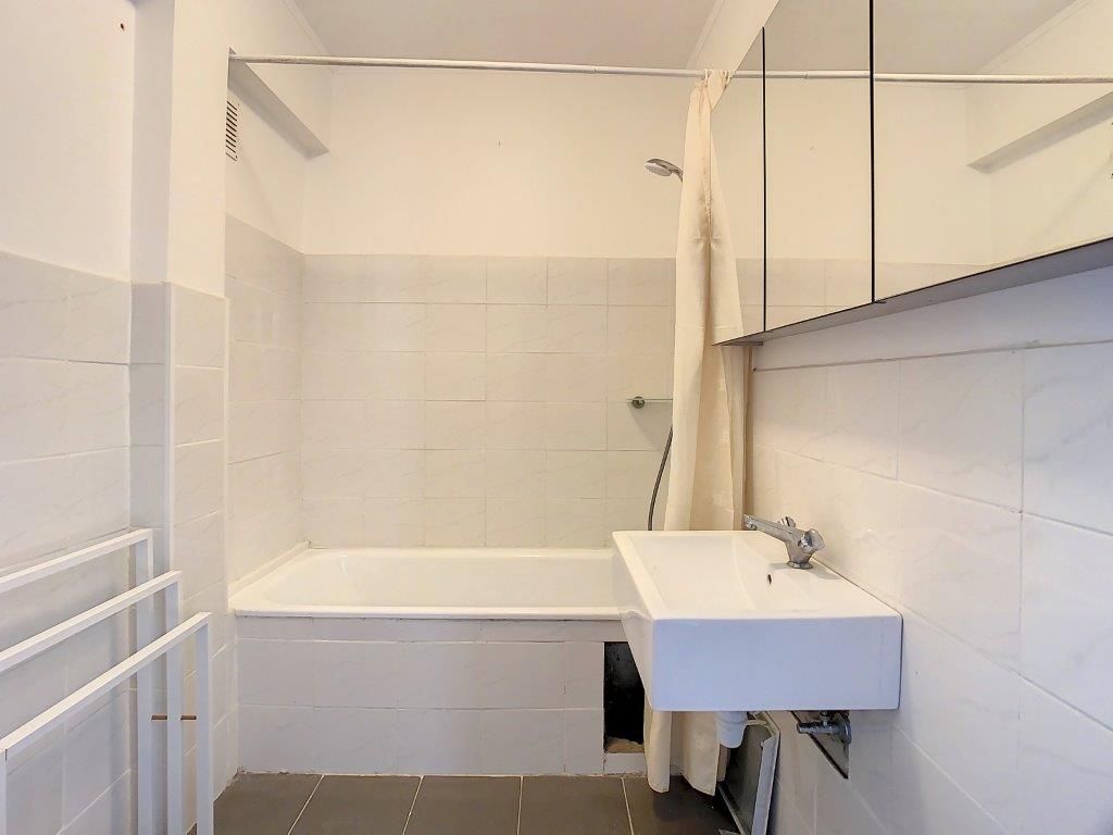 Salle de bain moderne minimaliste avec douche en verre, lavabo design et grand miroir lumineux.