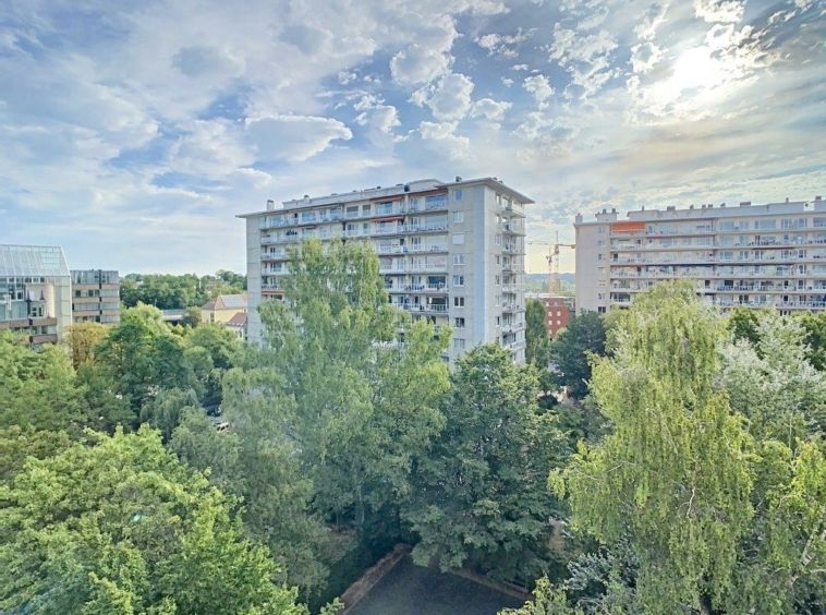 Immeubles modernes entourés de verdure sous un ciel ensoleillé, harmonies entre nature et urbanisme.