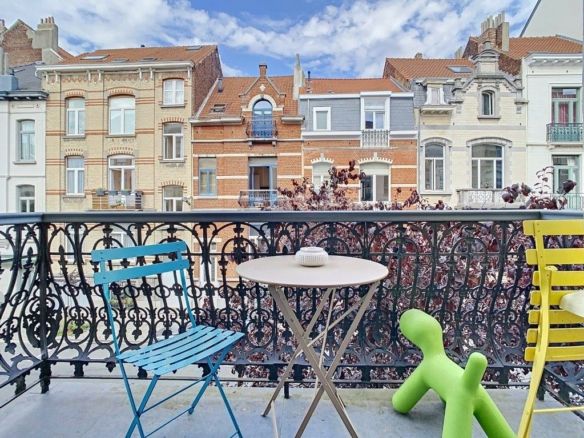 Colorful urban balcony with furniture, pastel view, blue sky, plants, relaxed, friendly atmosphere.