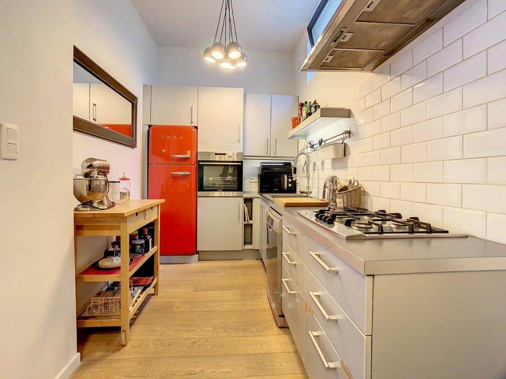 Cuisine moderne avec frigo rouge rétro, îlot en bois et éclairage élégant.