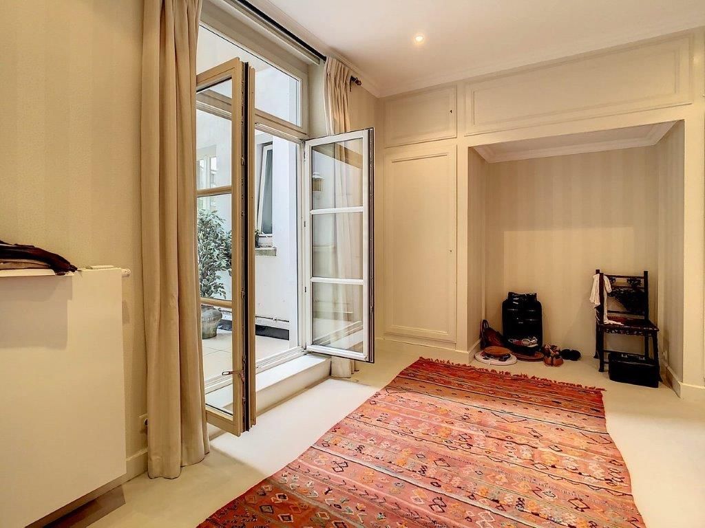 Salon lumineux élégant avec tapis coloré, grandes fenêtres, ambiance chaleureuse et décoration moderne.