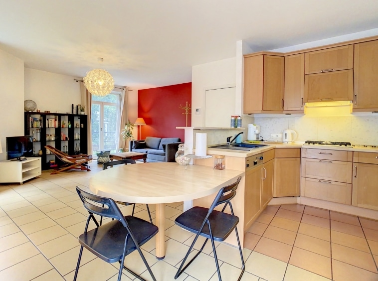 Espace de vie moderne avec cuisine en bois clair, coin repas convivial et déco chaleureuse.
