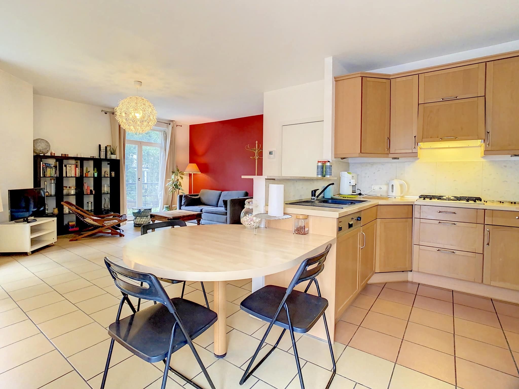 Espace de vie moderne avec cuisine en bois clair, coin repas convivial et déco chaleureuse.