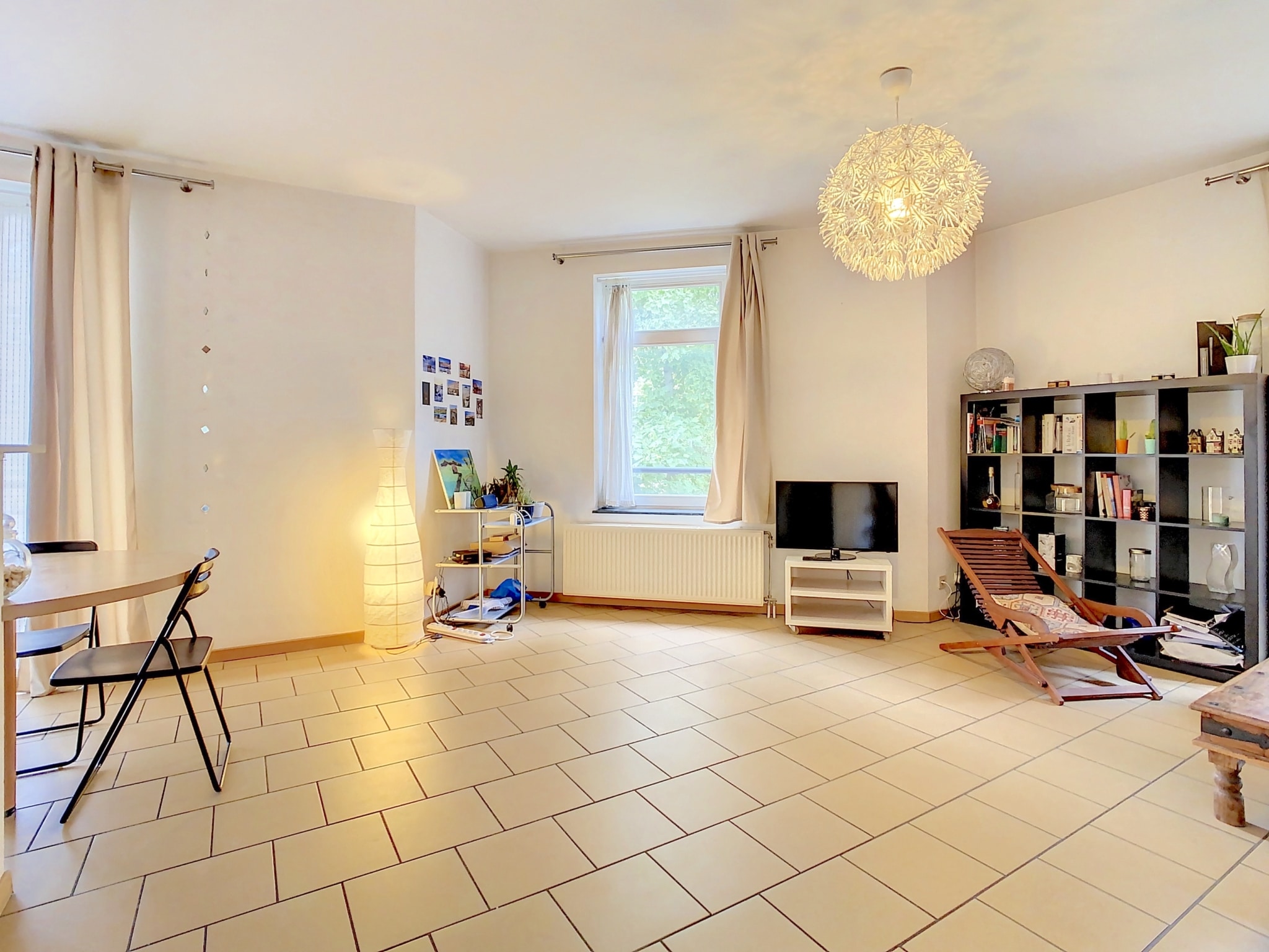 Salon lumineux, minimaliste avec mobilier élégant, grande fenêtre, ambiance chaleureuse et ouverte.