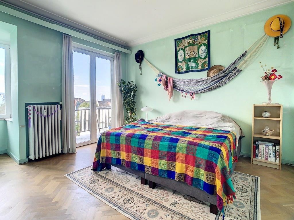 Chambre chaleureuse avec balcon, mur vert menthe, décoration colorée et ambiance apaisante.