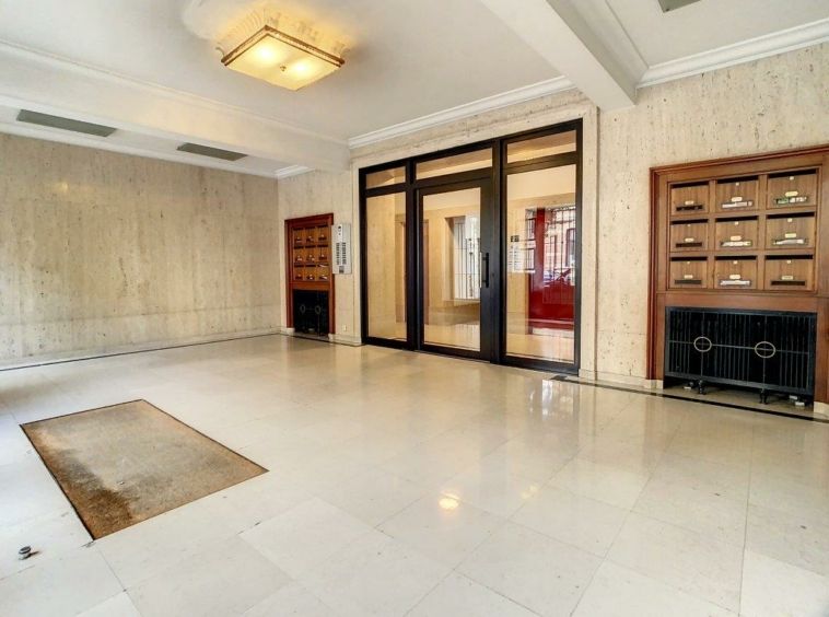 Entrée moderne lumineuse avec sol blanc, mobilier minimaliste et éclairage géométrique élégante.