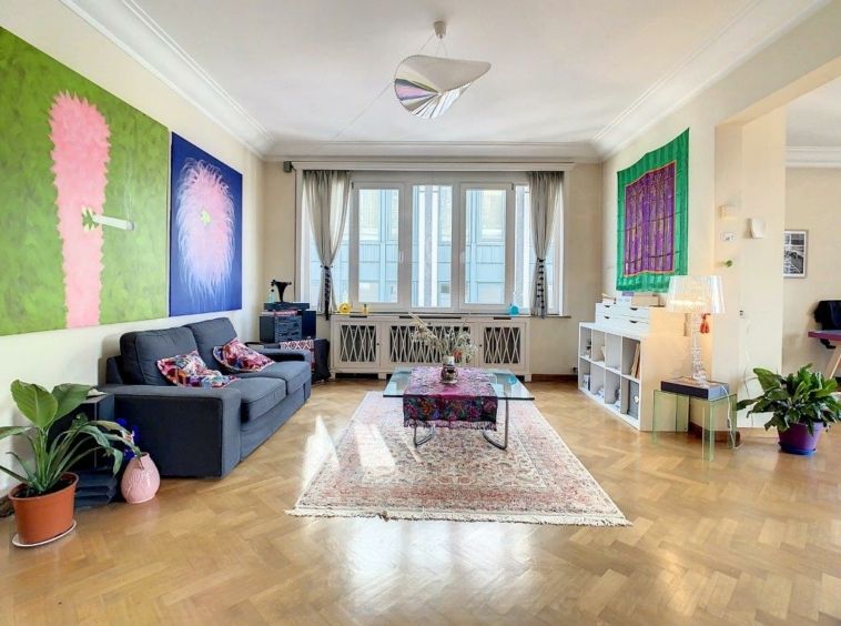 Salon contemporain coloré avec œuvres abstraites, plantes vertes et lumière naturelle.
