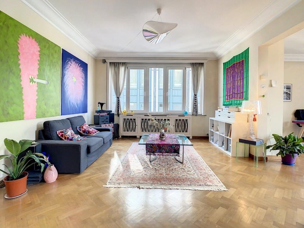 Salon contemporain coloré avec œuvres abstraites, plantes vertes et lumière naturelle.