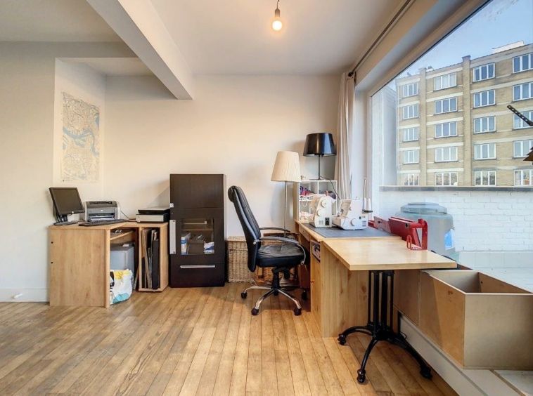 Bureau lumineux avec espace créatif, vue urbaine et décoration minimaliste en bois clair.