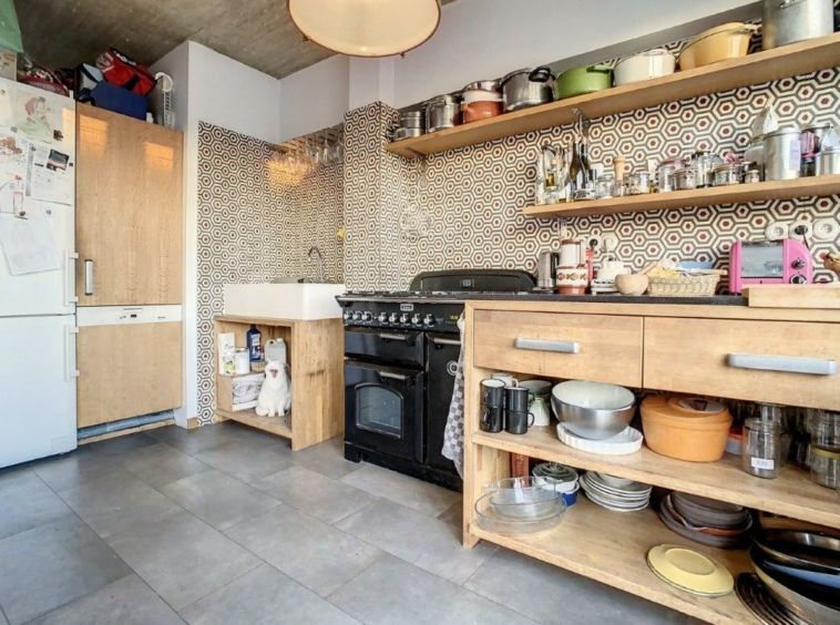 Cuisine moderne lumineuse avec plan en bois, équipements en acier et rangements ouverts.