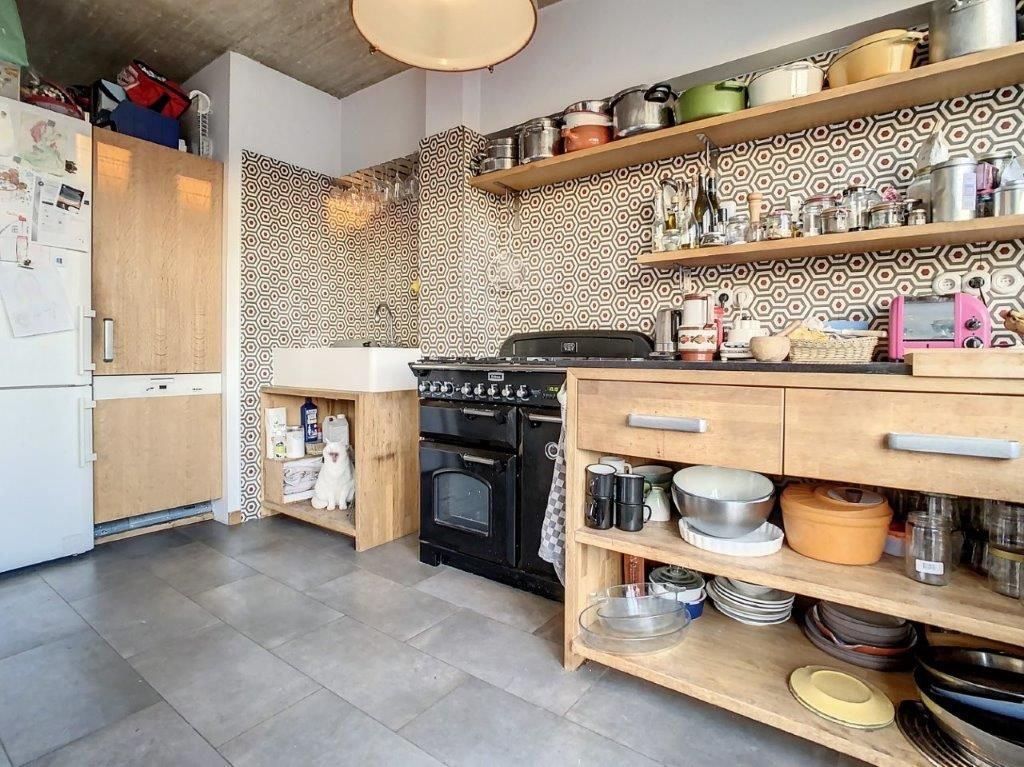 Cuisine moderne lumineuse avec plan en bois, équipements en acier et rangements ouverts.
